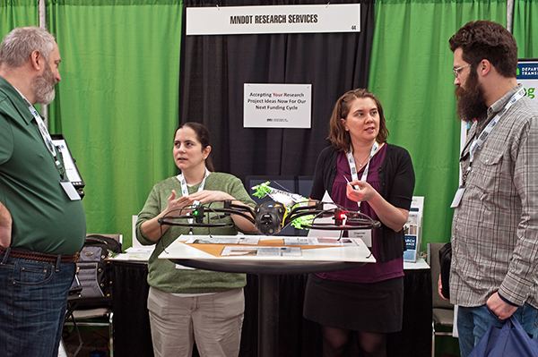 2 men and 2 women have a discussion at the MnDOT Research Services booth